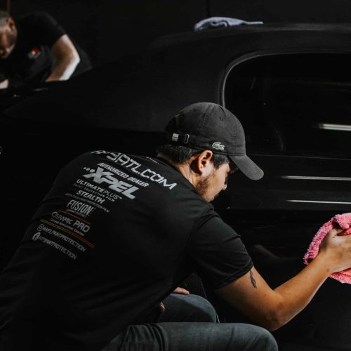 Technician applies ceramic coating to car as part of paint protection services
